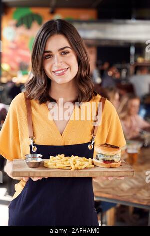 Portrait von Kellnerin Servieren von Speisen an Kunden in Bar Restaurant Stockfoto