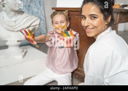 Kleine hübsche Mädchen mit bunten Palmen zu Kamera Stockfoto