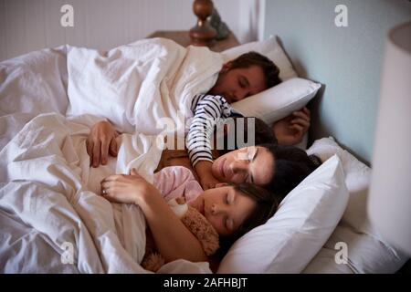 Mitte der erwachsenen Eltern und ihre zwei kleinen Kinder liegen schlafend im Bett, Taille, herauf, Nahaufnahme Stockfoto