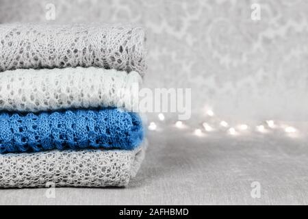 Stilvolle gestrickt, pastellfarbenen Pullover und eine trendige blaue Farbe in verschiedenen Strickmuster auf Samtigen Stoff Hintergrund stack gefaltet. Wint Stockfoto