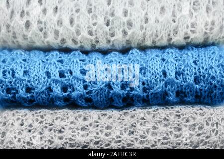 Stilvolle gestrickt, pastellfarbenen Pullover und eine trendige blaue Farbe in verschiedenen Strickmuster im Stapel gefaltet. Winter und Frühling saison Strickwaren Stockfoto