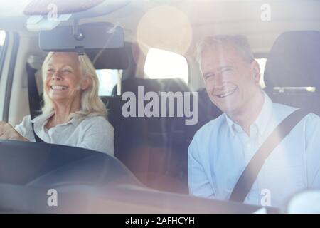 Happy senior weiß Frau fahren, ihr Ehemann im Beifahrersitz, durch die vordere Windschutzscheibe Stockfoto