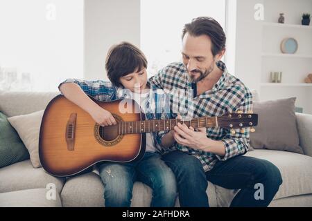 Am besten Wochenende Tätigkeiten überhaupt. Foto von zufriedenen Reife bärtige Papa ihr Sohn Gitarre spielen sitzen auf komfortablen Sofa genießen tragen Stockfoto