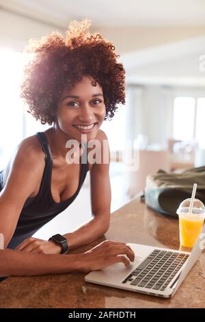 Tausendjährige afrikanische amerikanische Frau Kontrolle fitness Daten auf Notebook lächelnd in die Kamera, vertikal Stockfoto