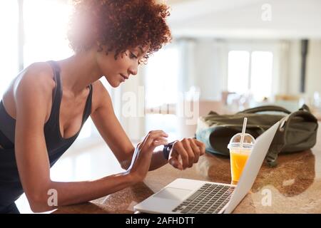 Tausendjährige afrikanische amerikanische Frau Kontrolle fitness App auf Beobachten und Laptop nach dem Workout, Seitenansicht Stockfoto