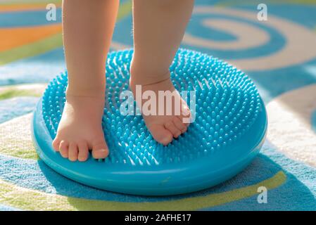 Ein kleines Kind seine Füße zu massieren und stehen auf dem Teppich Stockfoto