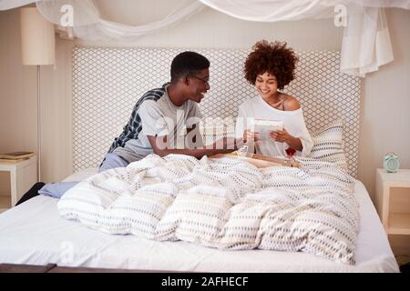 Tausendjährigen afrikanischen amerikanischen Mann seinen Partner Frühstück und Geschenke geben, im Bett zu feiern. Stockfoto