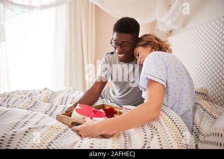 Mixed Race Paar, Mann seinen Partner Frühstück und Geschenke in Bett bringen, in der Nähe Stockfoto