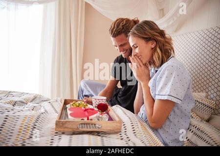 Tausendjährige weiße Mann überraschend seine Partnerin mit Frühstück und Geschenke im Bett, in der Nähe Stockfoto