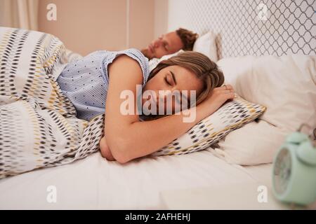 Tausendjährige weiß Paar schlafend im Bett, Wecker im Vordergrund, in der Nähe Stockfoto