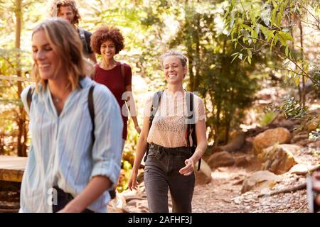 Lächelnd tausendjährigen Freundinnen zusammen zu Fuß bei einer Wanderung im Wald, in der Nähe Stockfoto
