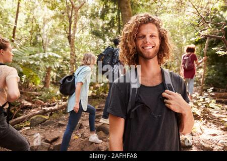Taille bis Portrait von lächelnden Tausendjährigen weiße Mann Wandern im Wald mit Freunden, in der Nähe Stockfoto