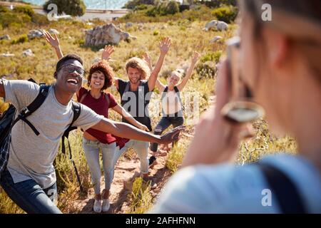Junge Erwachsene Freunde posieren und Fotos von jedem anderen während einer Wanderung bergauf auf einem küstenweg Stockfoto