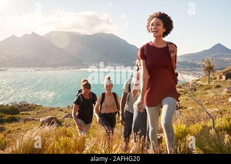 Tausendjährige afrikanische amerikanische Frau, die Freunde auf eine ansteigende Wanderung an der Küste, in der Nähe Stockfoto