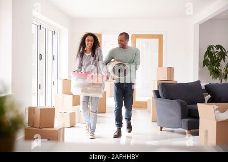 Lächelndes Paar Kisten in die neue Heimat am Umzugstag Stockfoto