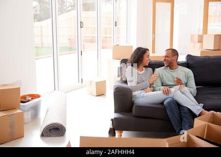 Paar eine Pause und Sitzen auf einem Sofa feiert Umzug in neues Haus mit Champagner Stockfoto
