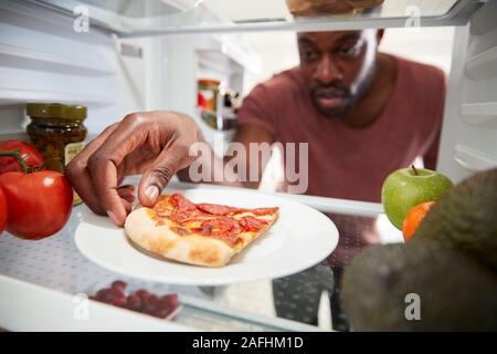 Anzeigen, die von der Innenseite der Kühlschrank als Mensch öffnet Tür für Übrig gebliebene Takeaway Pizza Stockfoto