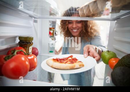 Anzeigen, die von der Innenseite der Kühlschrank als Frau öffnet Tür für Übrig gebliebene Takeaway Pizza