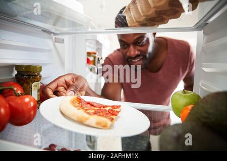 Anzeigen, die von der Innenseite der Kühlschrank als Mensch öffnet Tür für Übrig gebliebene Takeaway Pizza Stockfoto