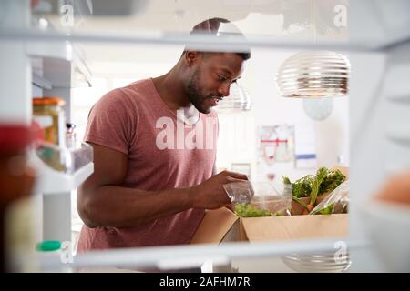 Blick aus dem Inneren der Kühlschrank als Mann packt Online Home Food Delivery Suchen Stockfoto