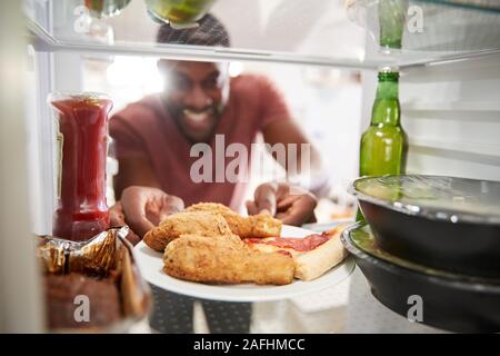 Anzeigen, die von der Innenseite der Kühlschrank gefüllt mit ungesunden Essen zum Mitnehmen als Mensch öffnet Tür Stockfoto