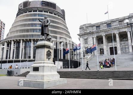Wellington, Neuseeland. 16 Dez, 2019. Nationale Fahnen der Neuseeland fliegen auf Halbmast vor dem Gebäude des Parlaments die Opfer der Weißen Insel vulkanischen Eruption in Wellington, Neuseeland zu gedenken, die am 16. Dezember, 2019. Fragen und in Bezug auf die Verluste durch die Weisse Insel Vulkanausbruch verursacht beantwortet werden, sagte Neuseeland Premierminister Jacinda Ardern am Montag. Menschen in Neuseeland beobachtet eine Schweigeminute am Montag zu Ehren der Opfer der Weißen Insel vulkanischen Eruption. Quelle: Guo Lei/Xinhua/Alamy leben Nachrichten Stockfoto