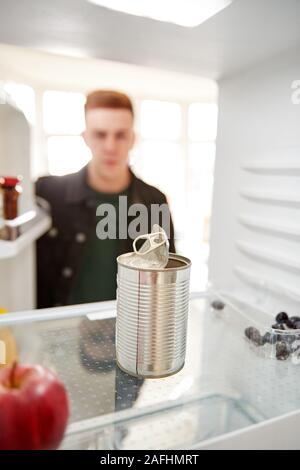 Junger Mann auf der Suche nach innen Kühlschrank leer, außer für die offene Dose im Regal Stockfoto