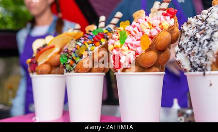 Bubble Waffeln mit Himbeeren, Schokolade und Marshmallows in white paper Cups sind auf offene Küche Food Festival verkauft. Hong Kong Waffeln. Anhand von quantitativen Simulatio Stockfoto