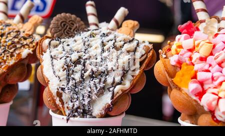 Bubble Waffeln mit Himbeeren, Schokolade und Marshmallows in white paper Cups sind auf offene Küche Food Festival verkauft. Hong Kong Waffeln. Anhand von quantitativen Simulatio Stockfoto