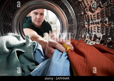 Blick aus dem Inneren Waschmaschine als junger Mann hat Wäsche suchen Stockfoto
