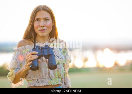 Frau im Sommerkleid holding Fernglas, Entfernungen Stockfoto