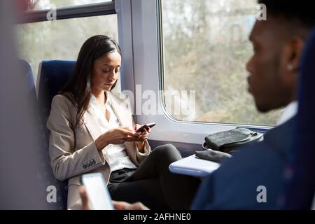 Business Passagiere sitzen im Zug pendeln auf Mobiltelefone zu arbeiten Stockfoto