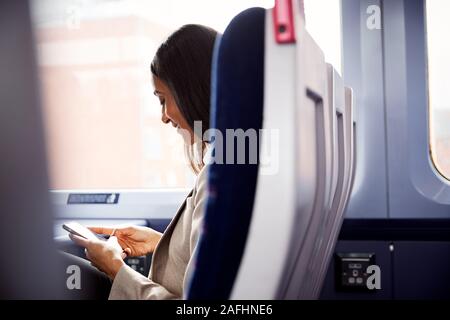Geschäftsfrau sitzt in dem Zug Pendeln zum Arbeitsplatz Abrufen von Nachrichten auf dem Handy Stockfoto