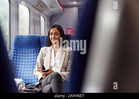 Geschäftsfrau sitzt in dem Zug Pendeln zum Arbeitsplatz Abrufen von Nachrichten auf dem Handy Stockfoto
