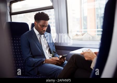Geschäftsmann sitzt in dem Zug Pendeln zum Arbeitsplatz Abrufen von Nachrichten auf dem Handy Stockfoto
