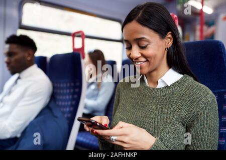 Weibliche Passagier sitzt im Zug am Handy suchen Stockfoto