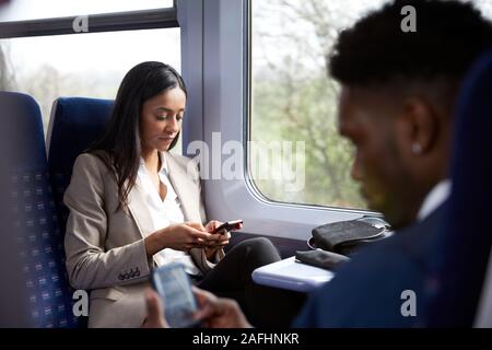 Business Passagiere sitzen im Zug pendeln auf Mobiltelefone zu arbeiten Stockfoto