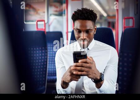 Geschäftsmann sitzt in dem Zug Pendeln zum Arbeitsplatz Abrufen von Nachrichten auf dem Handy Stockfoto