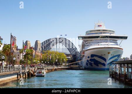 Sydney Harbour Cruise Ship - ein Kreuzfahrtschiff, der an einem sonnigen Tag im Sommer im Hafen von Sydney festgemacht ist, mit der Sydney Harbour Bridge dahinter, Sydney Australia Stockfoto