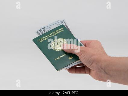 Hand hält aus Usbekistan Reisepass mit USA Dollar. Konzept - Bestechendem und Korruption Stockfoto