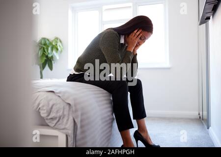 Betonte Geschäftsfrau mit Kopf in den Händen sitzen am Rande von Bett zu Hause Stockfoto