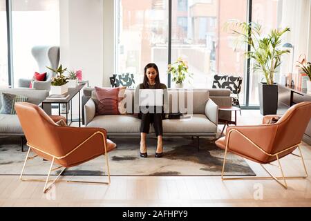 Geschäftsfrau, Sitzen auf einem Sofa Arbeiten am Notebook am Schreibtisch In gemeinsamen Arbeitsbereich Büro Stockfoto
