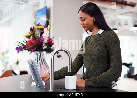 Geschäftsfrau Heiß Trinken von automatisierten Dispenser im Büro Stockfoto