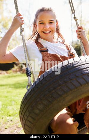 Portrait von Mädchen Spaß haben auf dem Reifen Schwingen im Garten zu Hause Stockfoto