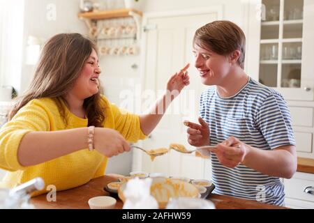 Junge Abstiegsyndrom Paar Spaß Baking Cupcakes in der Küche zu Hause.