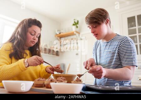 Junge Abstiegsyndrom Paar Dekorieren hausgemachte Cupcakes mit Zuckerglasur in der Küche zu Hause. Stockfoto