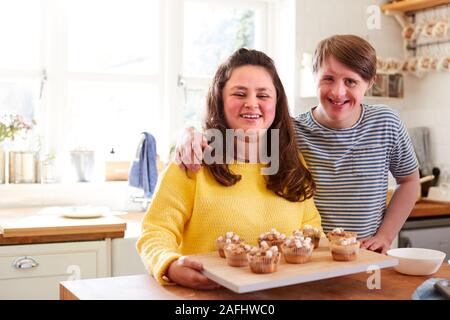 Portrait von Abstiegsyndrom Paar hausgemachte Muffins verzieren mit Marshmallows in der Küche zu Hause. Stockfoto