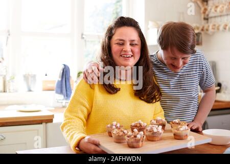 Portrait von Abstiegsyndrom Paar hausgemachte Muffins verzieren mit Marshmallows in der Küche zu Hause. Stockfoto