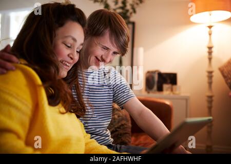 Junge Abstiegsyndrom Paar sitzt auf einem Sofa mit digitalen Tablette zu Hause Stockfoto