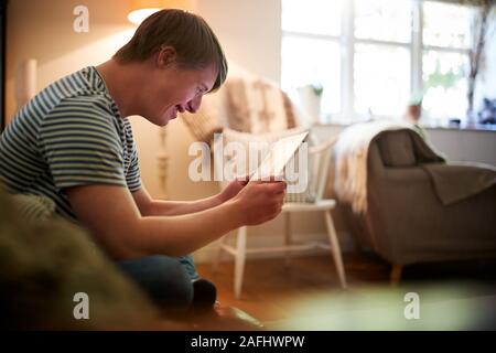 Junge Abstiegsyndrom Mann sitzt auf einem Sofa mit digitalen Tablette zu Hause Stockfoto